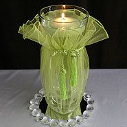 a green glass vase with a candle in it