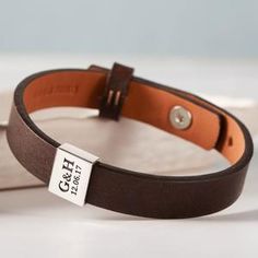 a close up of a leather bracelet with a tag on the clasp and an empty wallet in the background