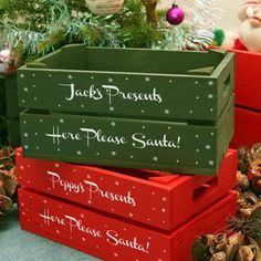 three wooden boxes stacked on top of each other in front of a christmas tree and decorations