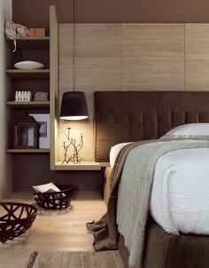 a bed sitting next to a wooden shelf filled with books on top of a hard wood floor