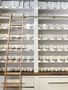 a ladder is in front of shelves with jars on them and bookshelves behind it