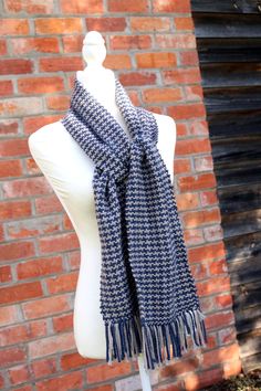 a mannequin wearing a blue and white scarf on top of a brick wall