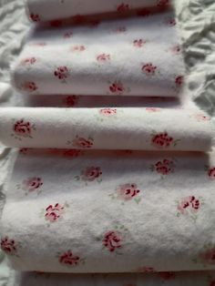 three rolled up towels sitting on top of a white sheet covered in pink and red flowers