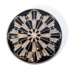 a black and gold brooch with diamonds in the shape of a sunburst