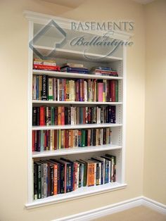 a book shelf filled with lots of books next to a wall mounted sign that reads basements building