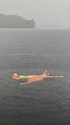 a person floating in the water on top of a body of water with an island in the background