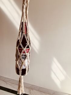 a bottle hanging from a rope in a room with white walls and marble flooring