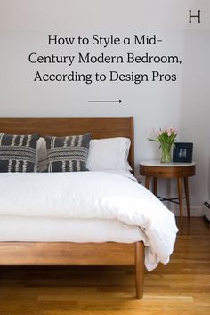 a bed with white sheets and pillows in a bedroom next to a wooden nightstand table