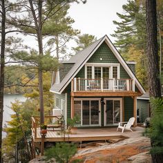 a house with a deck in the woods next to a body of water and trees