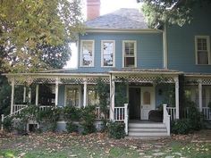 a large blue house sitting in the middle of a yard with lots of leaves on the ground