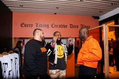 three men standing in front of a clothing store looking at something on the wall behind them