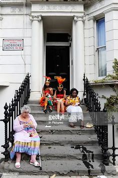 three women sitting on the steps of a house with halloween decorations in front of them