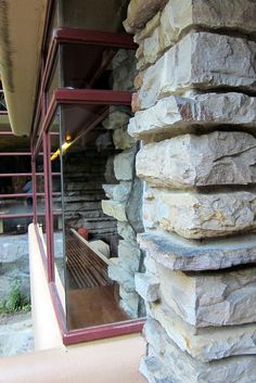 a stack of rocks sitting next to a window on top of a stone wall in front of a building