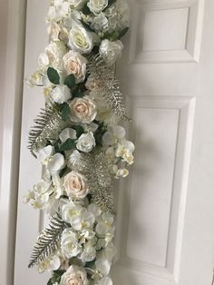 white flowers and greenery are hanging on the door