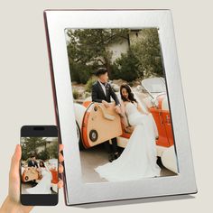 a person holding a cell phone in front of an image of a bride and groom