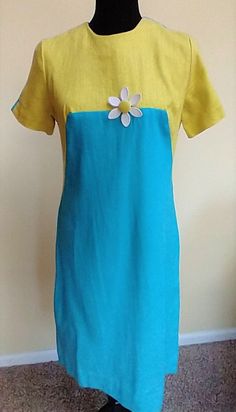 This gorgeous pencil silhouette dress is a linen feel material.  The cut and make of the dress is quality.  The colors are a vibrant blue and yellow and the daisy pin adds a 1960s touch.  It is too very classy and because the fabric is natural it would be comfortable to wear.  It closes with a zipper up the back.  It has some nobs in the fabric, but I told that this is natural and not from wear.   The dress was most likely worn by my elderly neighbor when she worked in the bank.  It's been stored for a long time and washed and steamed and ready for a new home. Dress is a small and the measurements are: Neck 6.25" Shoulder to shoulder 14" Armpit to armpit 17.5 Waist 16" Hips 17.5 Length  38" There is no stretch in the fabric so measure carefully for a great fit! Fitted Blue Linen Dress, Fitted Yellow Linen Dress, Yellow Fitted Linen Dress, Yellow Linen Short Sleeve Dress For Summer, Fitted Blue Linen Dress For Spring, Yellow Fitted Short Sleeve Dress, Blue Fitted Knee-length Linen Dress, Blue Short Sleeve Linen Dress For Summer, 1950s Shirtwaist Dress