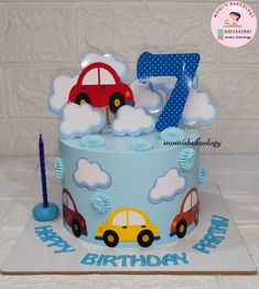 a blue birthday cake with cars and clouds on the top is for a seven year old