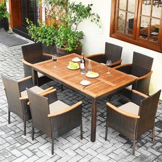 an outdoor dining table and chairs set up on a brick patio with potted plants