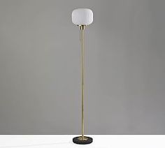 a floor lamp with a white shade on the top and a black base in front