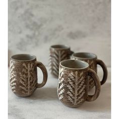 three coffee mugs sitting next to each other on a white tablecloth covered surface