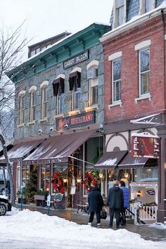 people are walking down the street in front of stores on a snowy day with no one around