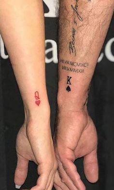 two people holding hands with tattoos on their arms and wrist, one has a red heart