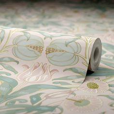 a roll of toilet paper sitting on top of a floral print wallpaper covered in green and pink flowers