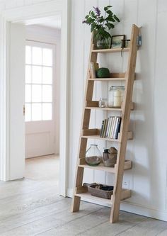 a wooden ladder leaning against the wall with books on it and plants in vases