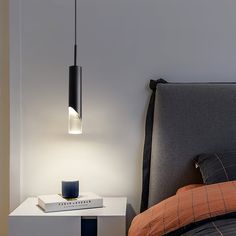 a lamp that is on top of a nightstand next to a bed with a book