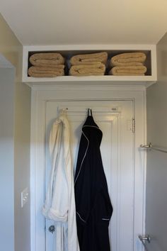 an open door with towels hanging on the shelf above it and two folded white towels in front of them