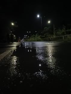 the street is flooded with water and lights shine brightly in the dark sky above it