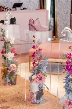 three clear vases filled with flowers and shoes