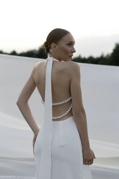 a woman in a white dress standing with her back to the camera