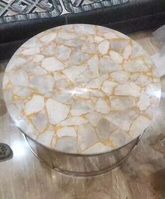 a white marble coffee table sitting on top of a hard wood floor next to a couch