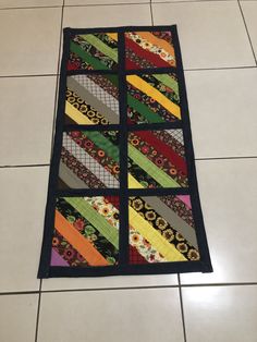 a multicolored patchwork quilt laying on the floor next to a tiled floor