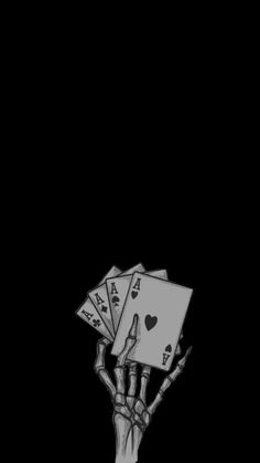 a hand holding playing cards in the dark