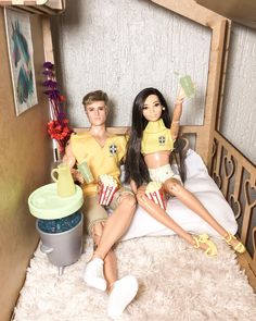 two dolls are sitting on a bed together