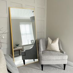 a living room with a chair and a large mirror on the wall next to it