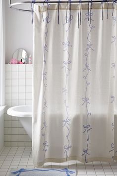 a bathroom with a shower curtain that has blue vines on it, and a bathtub in the background