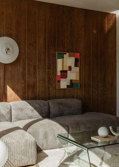 a modern living room with wood paneling and striped couches, coffee table and lamp