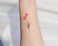 a woman's arm with a small tattoo of three flowers on the left wrist