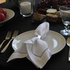 a table set with silverware, wine glasses and napkins