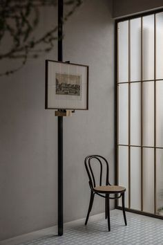 a chair sitting in front of a window next to a table with a lamp on it