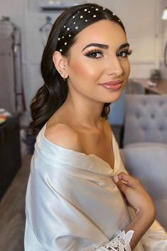 a woman with long hair wearing a white dress and pearls in her hair is posing for the camera