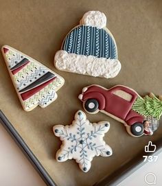 three decorated cookies sitting on top of a cookie sheet next to a christmas tree and snowflake