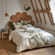 a bed with white sheets and green leaves on it