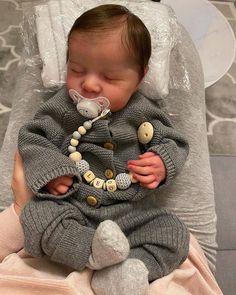 a baby is laying down with a pacifier in it's mouth and wearing a sweater