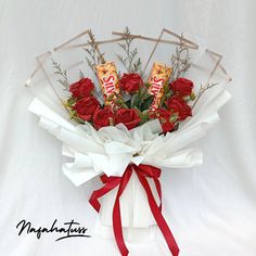 a bouquet of red roses and chocolate bars wrapped in white paper