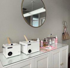 two white boxes sitting on top of a counter in front of a mirror and other items