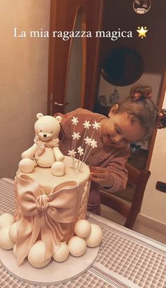 a woman is decorating a cake with white flowers and teddy bears on the top